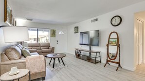 A living room with a sofa, coffee table, TV, and a mirror.