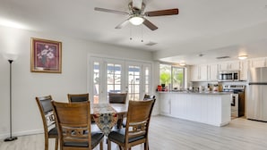A modern kitchen with white cabinets, a central island, and a dining area with wooden chairs and a table.
