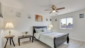A bedroom with a bed, two bedside tables, a ceiling fan, and a window.