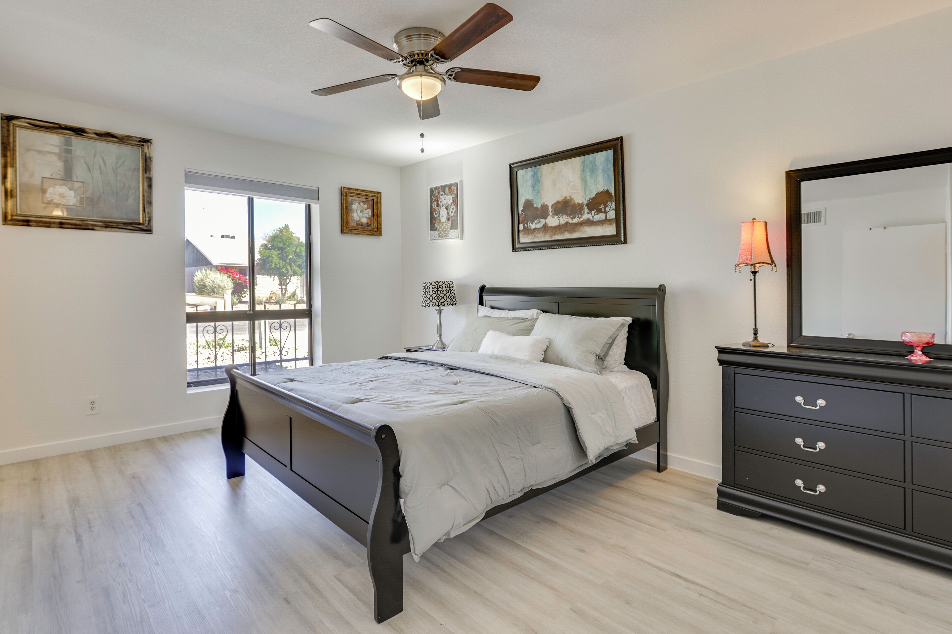 Une chambre à coucher avec un lit, un ventilateur de plafond, une commode et une fenêtre.