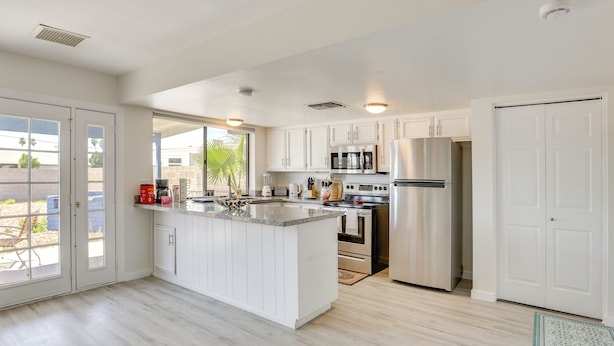 A modern kitchen with white cabinetry, stainless steel appliances, and a large island.