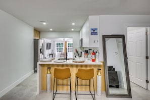 A modern kitchen with a central island, bar stools, a large mirror, and a door leading to another room. - Cozy Fort Lauderdale Home w/ Yard: 7 Mi to Beaches (Fort Lauderdale)