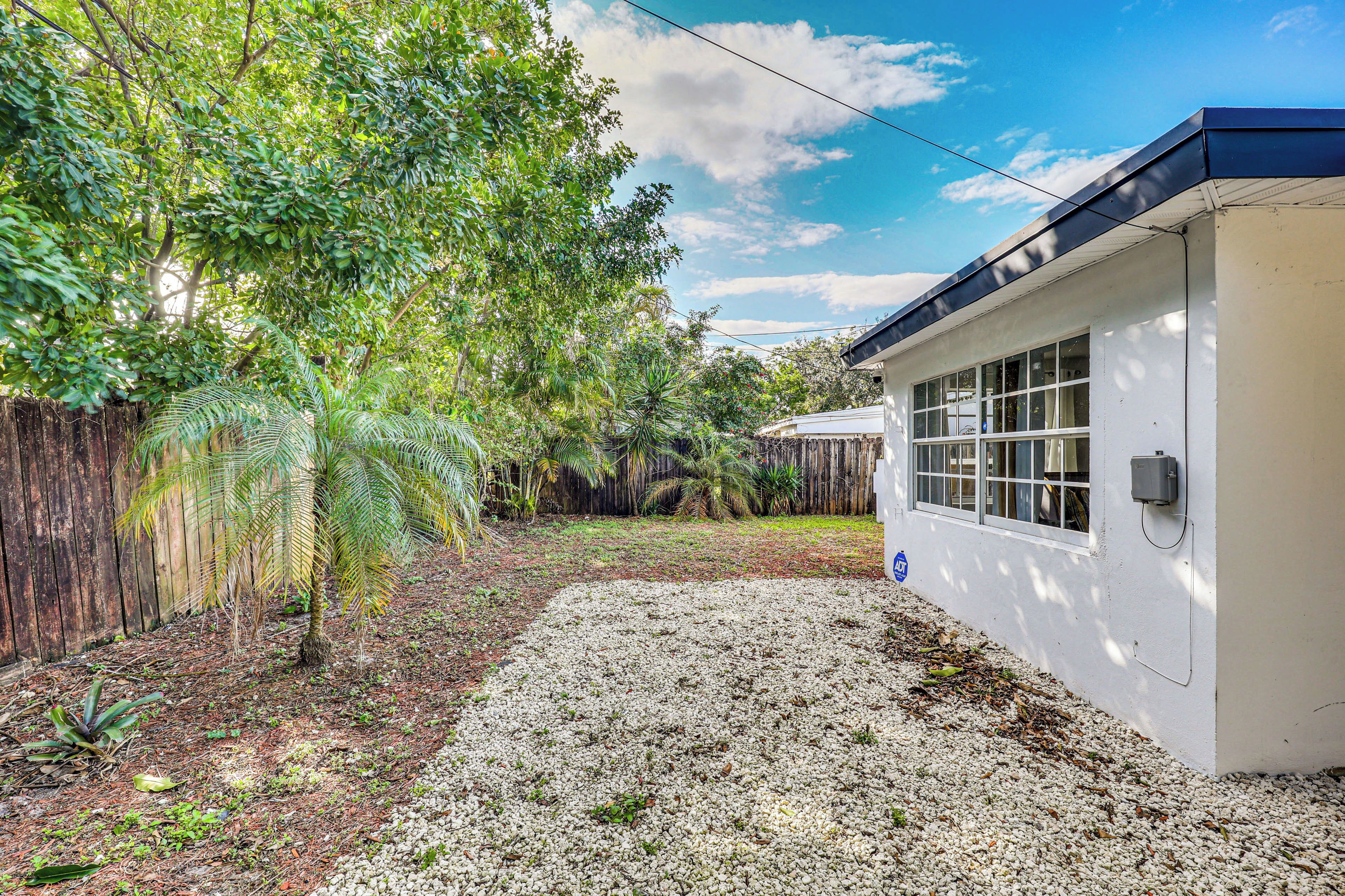 A building with a white exterior, a gravel driveway, and a wooden fence.