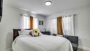 Ein Hotelzimmer mit Bett, Nachttisch, Sessel und einem Bild an der Wand.