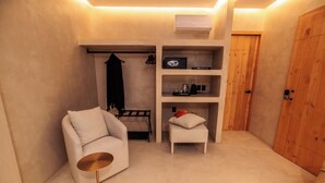 A compact room with a sofa, a small table, a shelf with items, a coat rack, and a wooden door. - Casa Rosario Bed & City Oaxaca (Oaxaca)