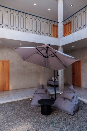 A spacious indoor area with a large umbrella, seating, and a staircase. - Casa Rosario Bed & City Oaxaca (Oaxaca)