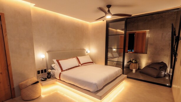 A modern bedroom with a bed, bedside lamps, a ceiling fan, and a large mirror. - Casa Rosario Bed & City Oaxaca (Oaxaca)