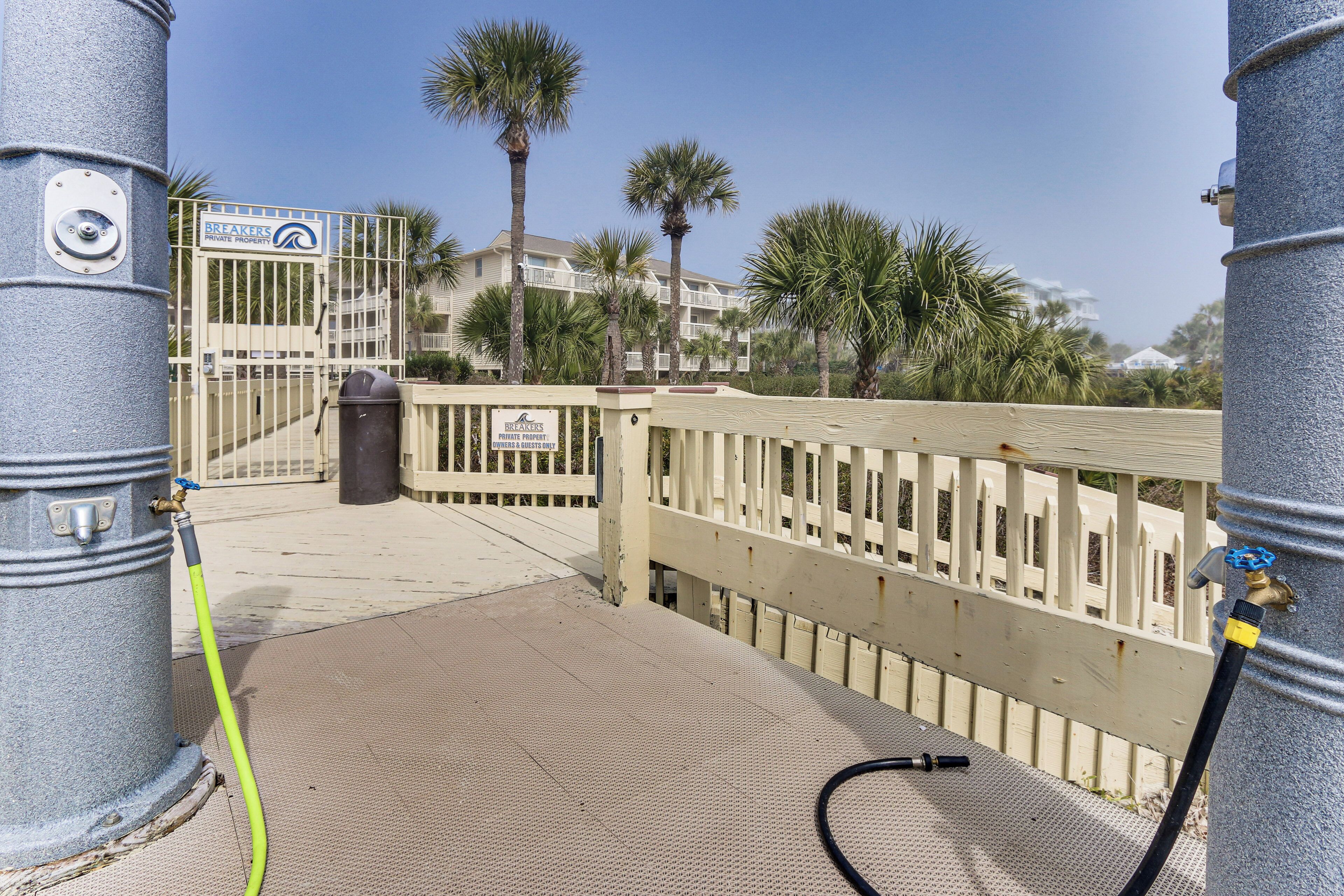 Una entrada cerrada con un letrero que dice 'Breakers Private Properties', una fuente de agua y palmeras al fondo.