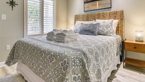 A bedroom with a bed, a bedside table, a lamp, a window with blinds, and a wall-mounted compass. - Beachfront Getaway! Hilton Head Resort Condo (Hilton Head Island)