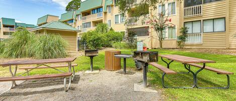 Een binnentuin met picknicktafels en een barbecue, omgeven door appartementen met balkons en groene daken.