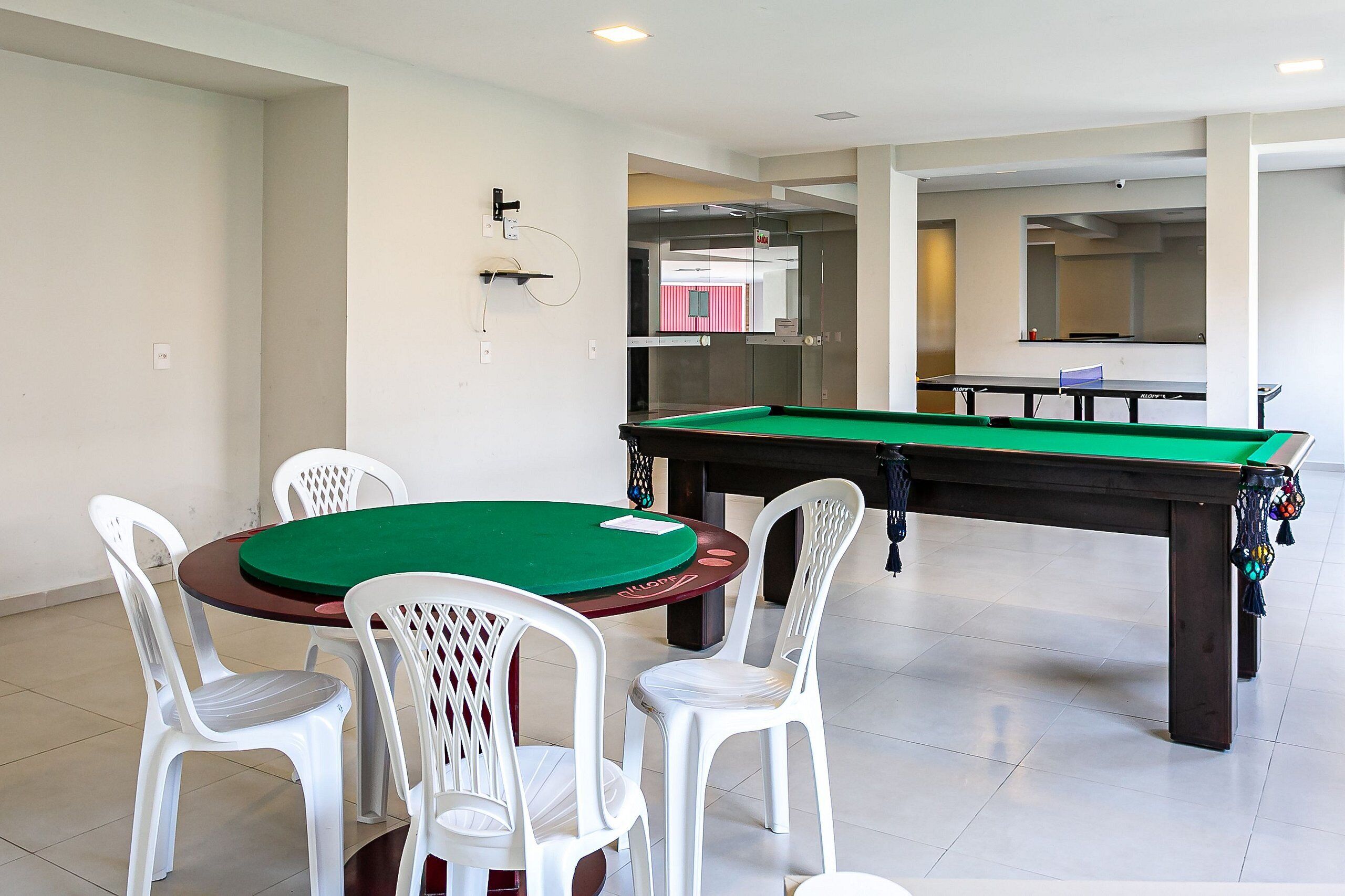 A billiards table with four chairs, a pool table, and a mirror on the wall.