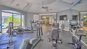 Una palestra con diverse attrezzature per l'allenamento, ampie finestre e una ventola a soffitto.