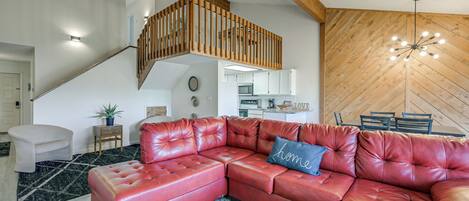 Ein modernes Wohnzimmer mit einem roten Ledersofa, einer Treppe und einer Holzwand.