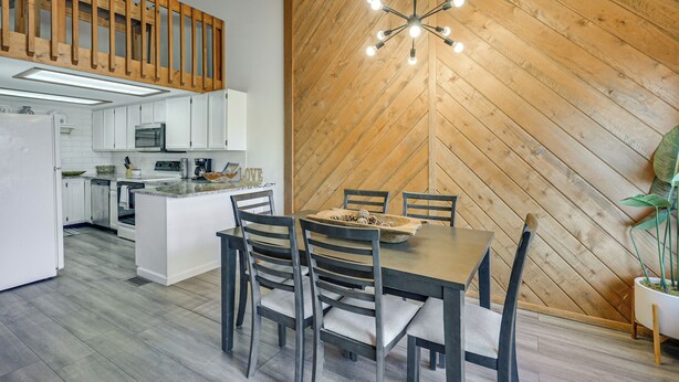 A modern kitchen with white cabinets, a central island, and a dining area with a wooden table and chairs. - Near Hiking! Family-friendly Pagosa Springs Haven (Pagosa Springs)