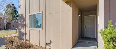 Un edificio con entrada principal, una puerta, un ventanal y un pequeño porche.