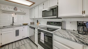A modern kitchen with white cabinetry, a granite countertop, a built-in microwave, a stove, and a coffee maker. - Near Hiking! Family-friendly Pagosa Springs Haven (Pagosa Springs)