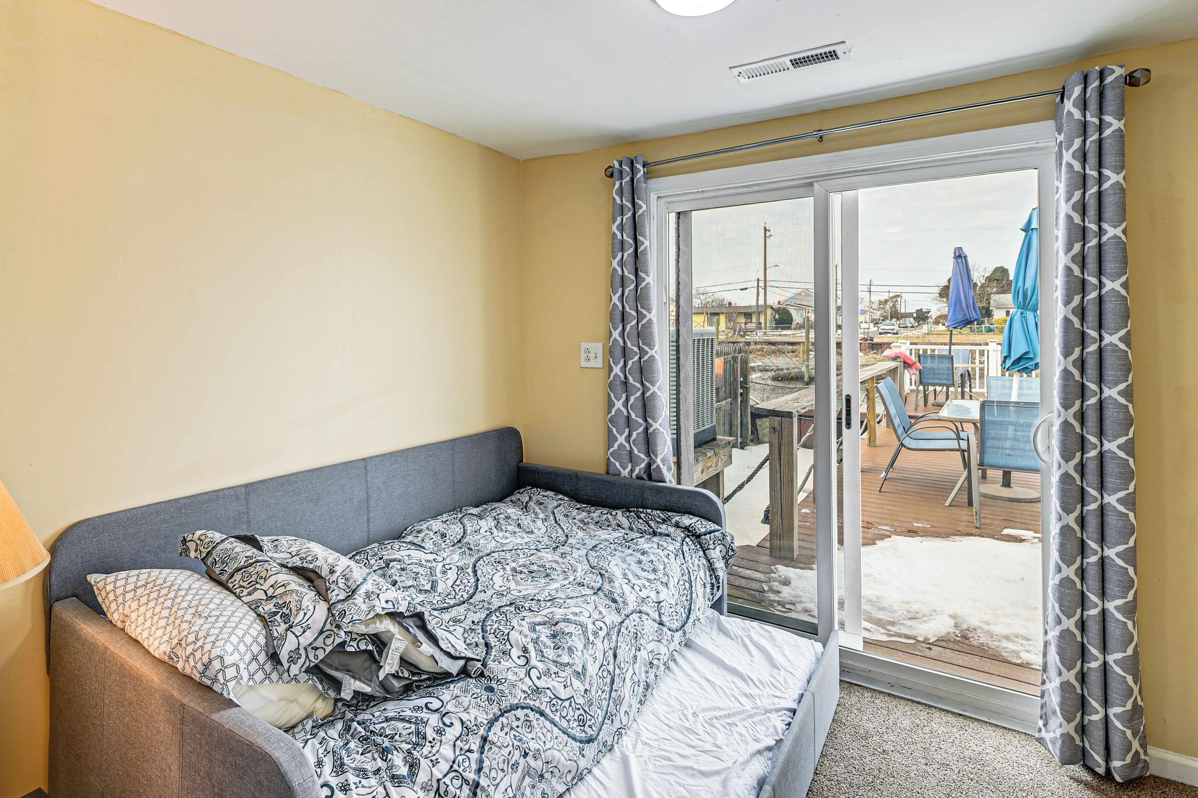 Ein Zimmer mit Bett, Fenster und Blick auf eine Außenpatio-Terrasse.