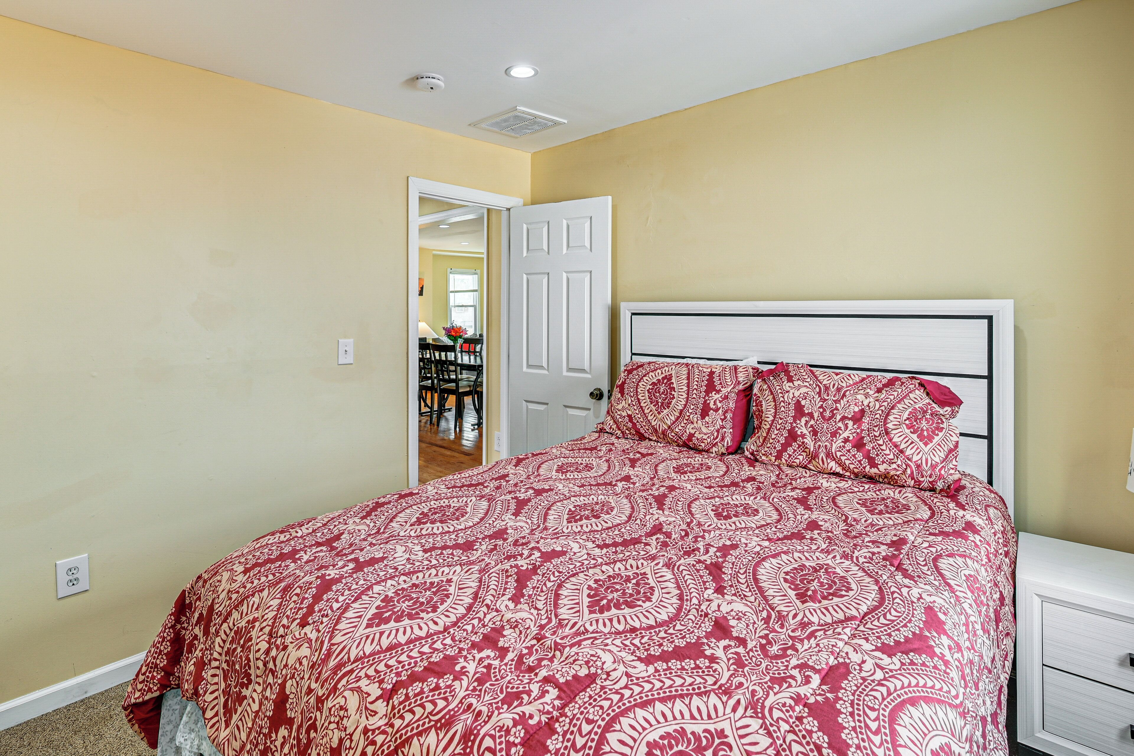 Un dormitorio con una cama, una mesita de noche y una puerta que da a otra habitación.