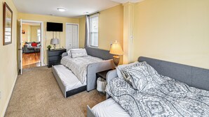 Een slaapkamer met twee bedden, een televisie, een lamp en een deur die naar een andere kamer leidt.
