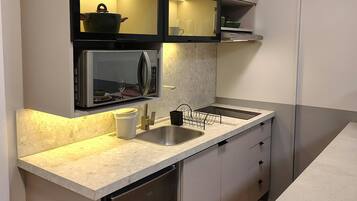 A modern kitchen with a built-in microwave, stainless steel sink, and a dishwasher.