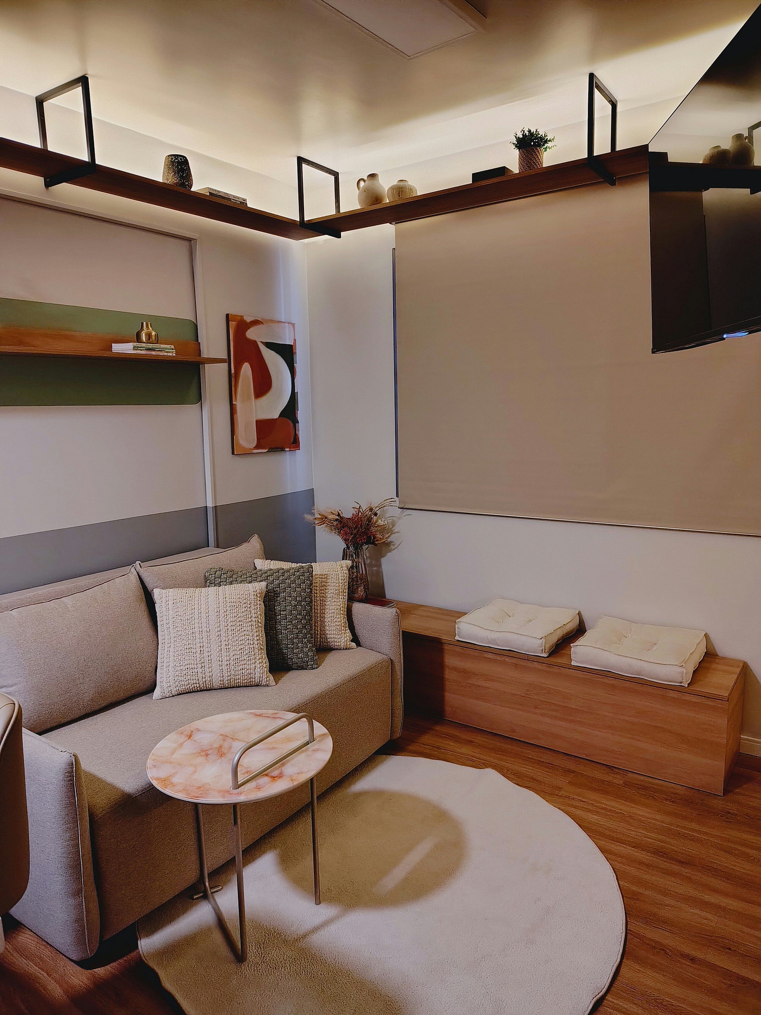 Uma sala de estar moderna com um sofá, mesa de centro e uma TV de tela plana na parede.