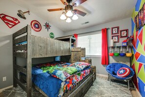 A bunk bed with a colorful bedspread, a ceiling fan, and superhero-themed wall decorations. - Backyard Oasis w/ Pool! Family Home in St George (St. George)
