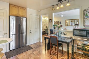 A kitchen with a stainless steel refrigerator, a dining table, and a bar area with a microwave. - Charming Boutique Home in West End Alexandria! (Alexandria)
