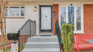 Une entrée d’habitation avec une porte d’entrée, des marches, une boîte aux lettres et un banc.
