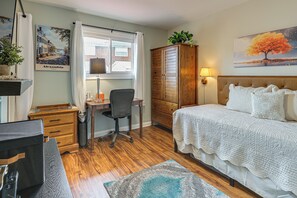 Ein Schlafzimmer mit Bett, Schreibtisch, Stuhl, Kleiderschrank und einem Fenster mit Vorhängen.