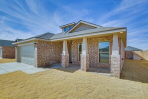 A residential house with a brick exterior, a garage, and a covered front porch.