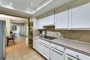 A kitchen with white cabinets, a granite countertop, and a tiled floor.