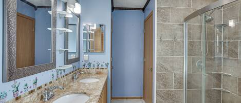 Un baño con dos lavamanos, cabina de ducha de vidrio y espejo con iluminación.