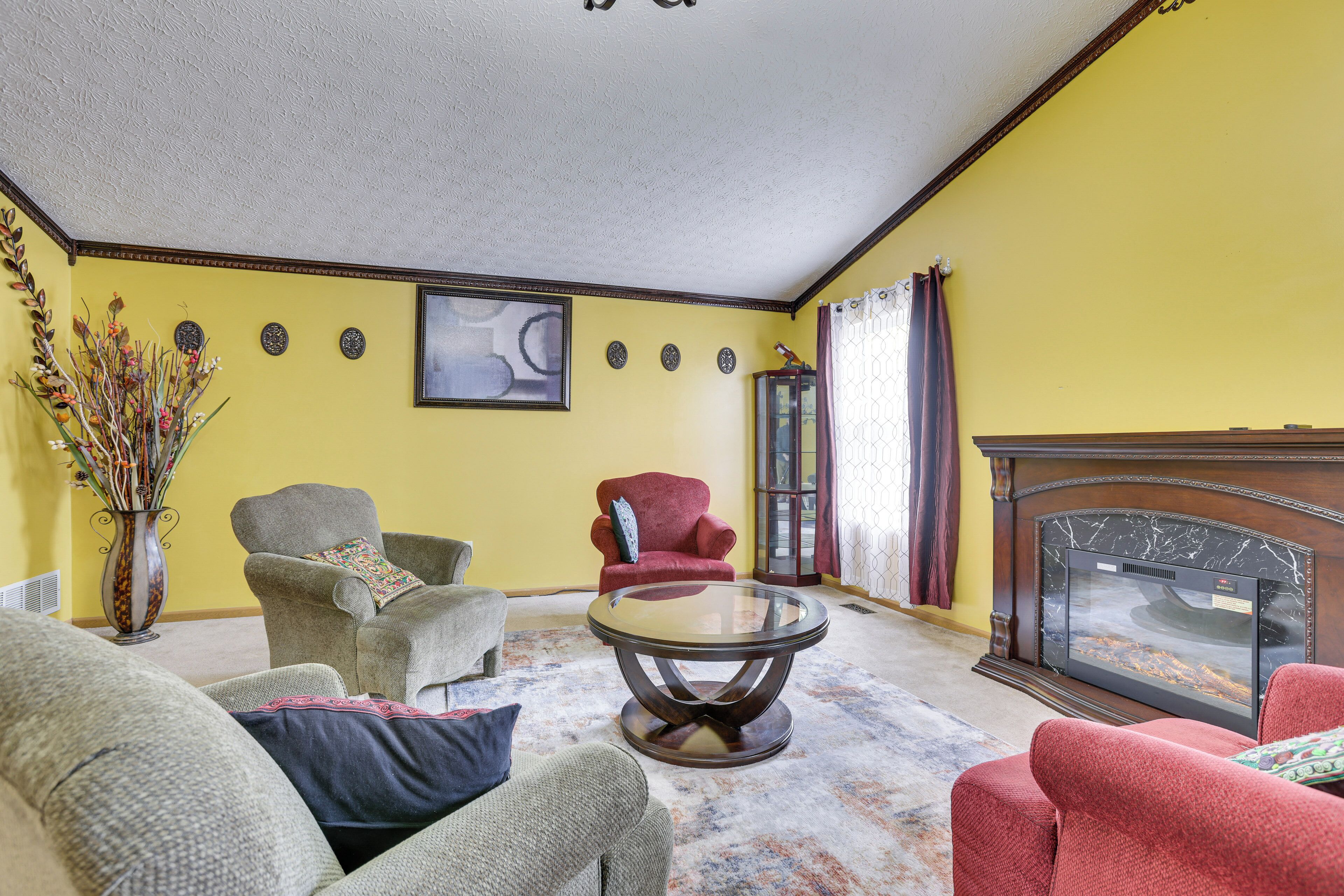 A living room with a fireplace, a coffee table, and two armchairs.