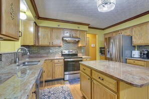 A kitchen with wooden cabinets, a stainless steel refrigerator, a double oven, and a granite countertop. - 6 Mi to Rickenbacker Airport! Columbus Area Home (Groveport)
