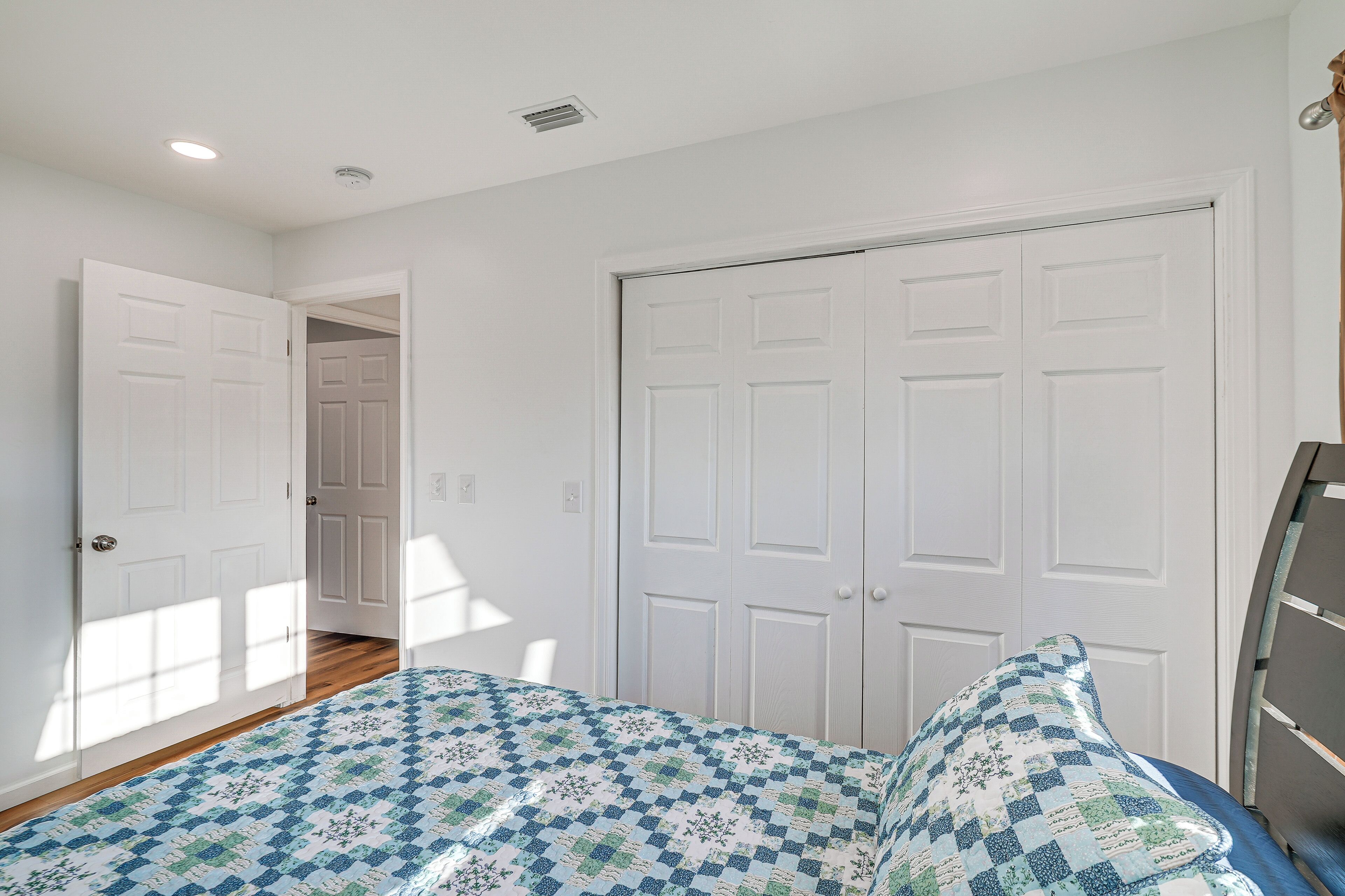 Un dormitorio con cama, puertas blancas y un pasillo.