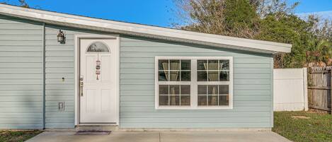 A single-story house with a front door, a small porch, and a window.