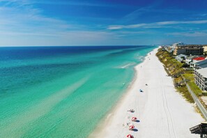 A beach with clear turquoise water, white sand, and a row of buildings with balconies along the shore. - Resort Pool, Golf Cart Included, Close to Beach, Gated Community (Santa Rosa Beach)