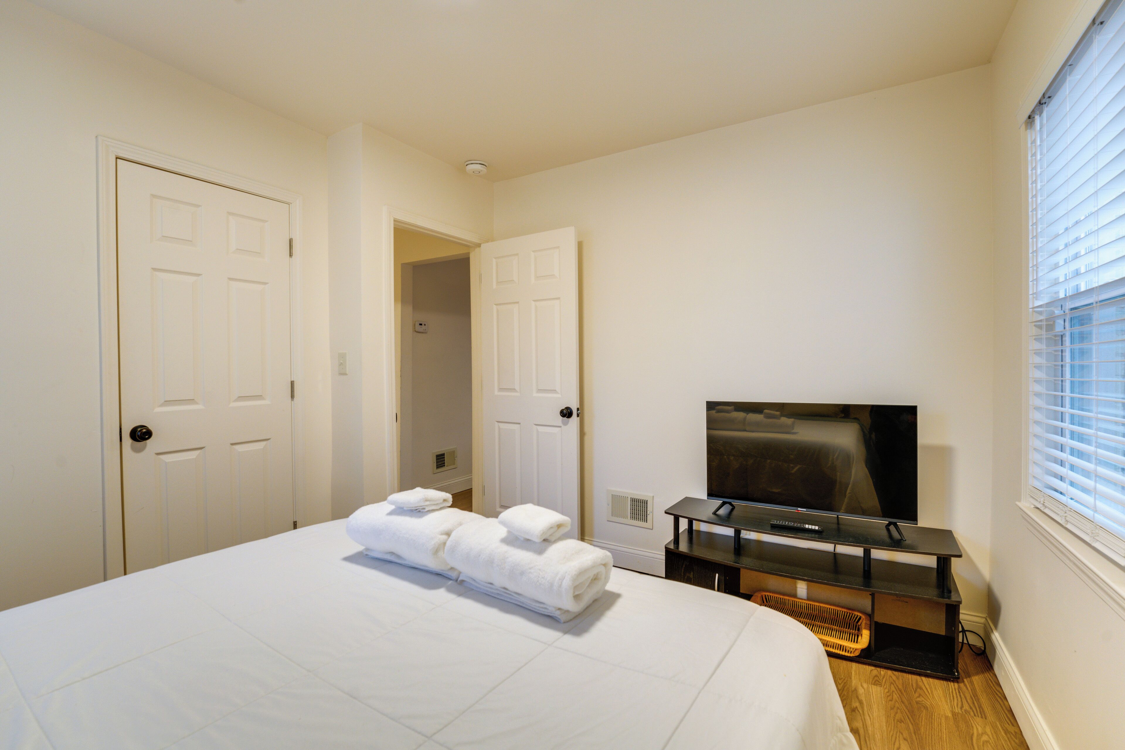 A bedroom with a bed, a TV, and a door leading to another room.