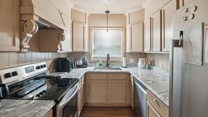 A kitchen with a stove, sink, and refrigerator, wooden cabinets, and a window with blinds. - Walk to Dining & Art: University District Gem! (Detroit)