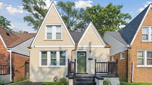A two-story house with a green door, white windows, and a brick exterior. - Walk to Dining & Art: University District Gem! (Detroit)