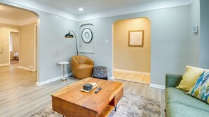 Un salon moderne avec une table basse en bois, un canapé vert et un tapis à motifs.