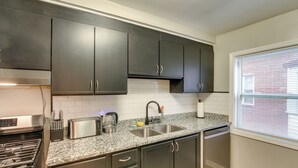 Une cuisine avec des meubles de couleur sombre, une cuisinière en acier inoxydable, un grille-pain et un évier.