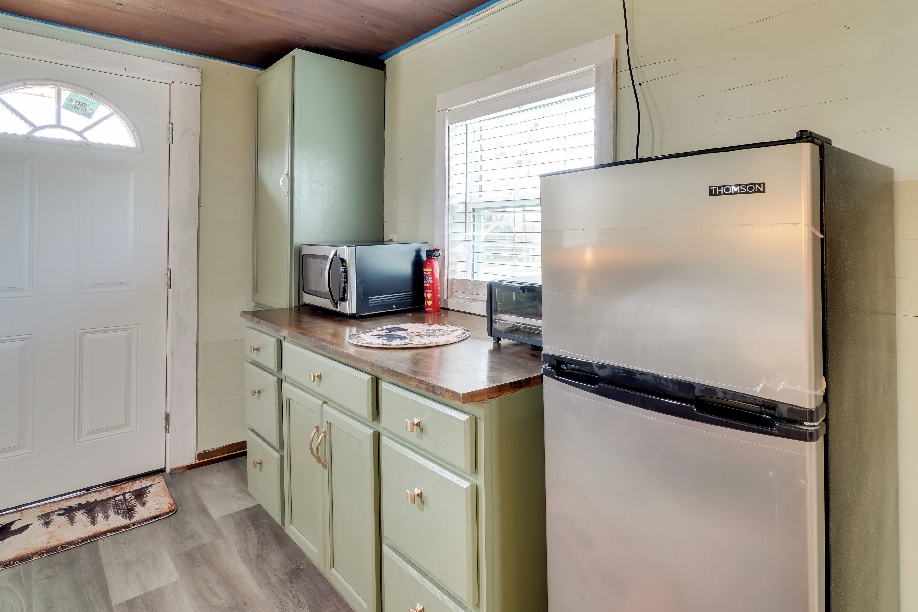 A kitchen with a THOMSON refrigerator, a microwave, and a toaster on the counter.