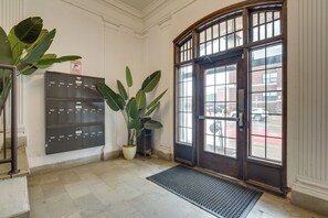 A lobby with a large metal door, a potted plant, and a metal mat at the entrance. - 1 Mi to Comerica Park: Convenient Couple's Retreat (Detroit)