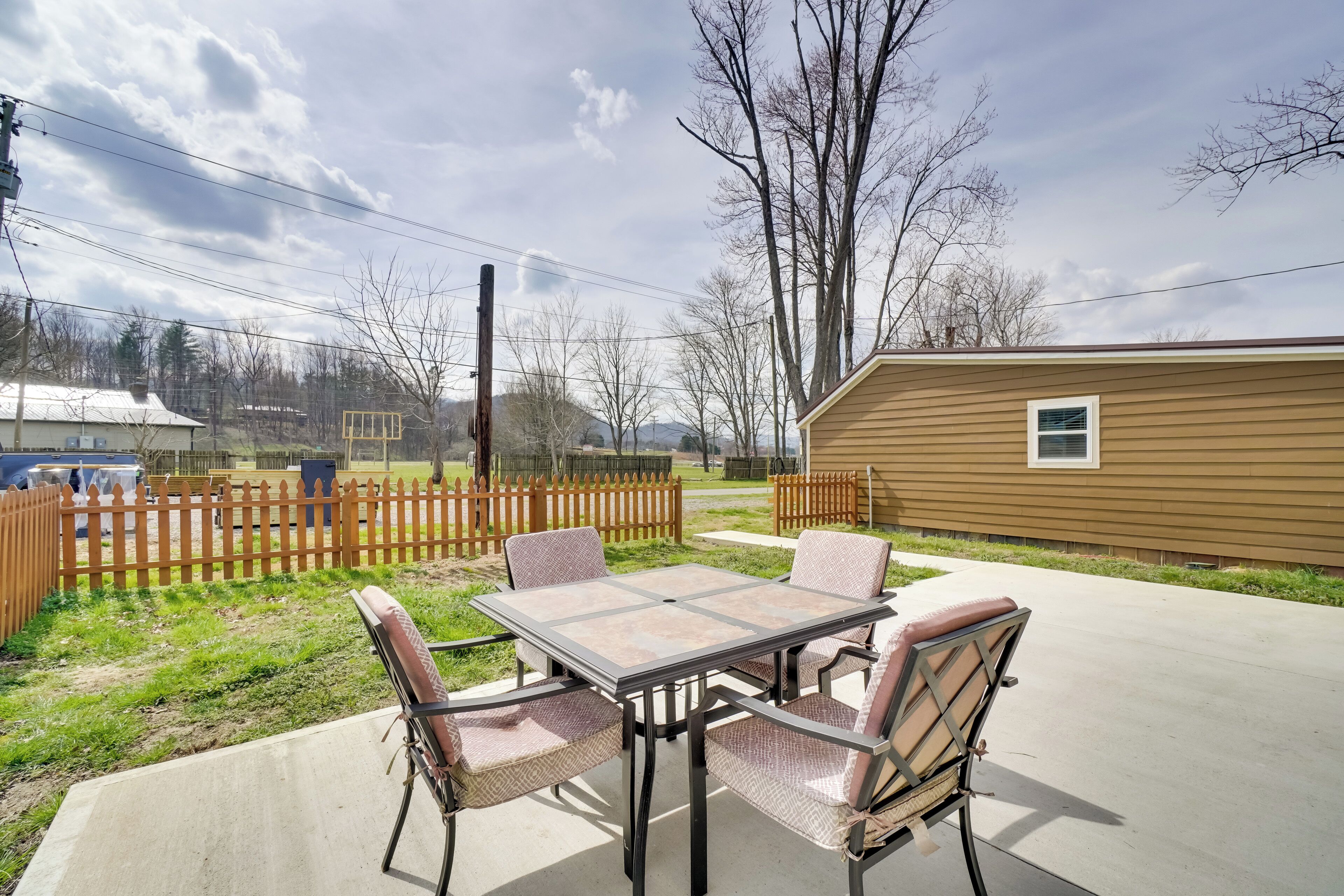 Une terrasse avec une table et des chaises, une clôture en bois et un petit bâtiment en arrière-plan.