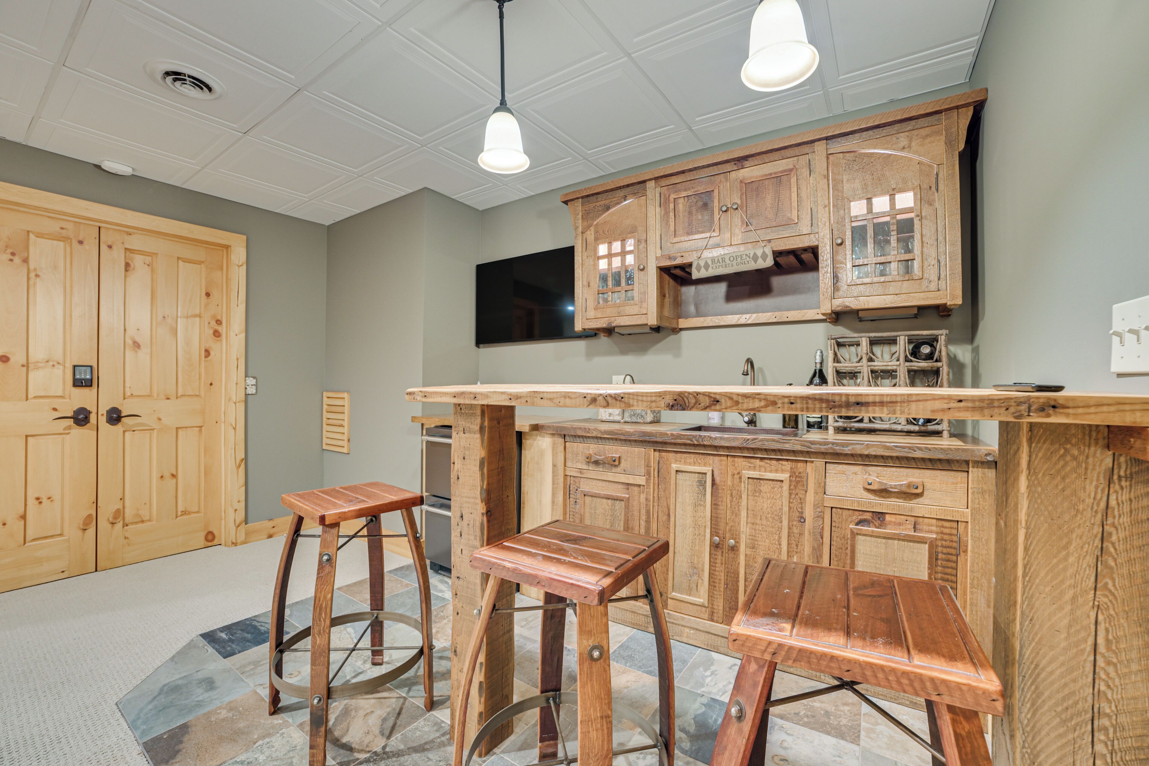 Una cucina con mobili in legno, un angolo bar e due sgabelli.