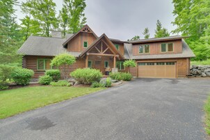 A log cabin with a garage, surrounded by a well-maintained lawn and trees.