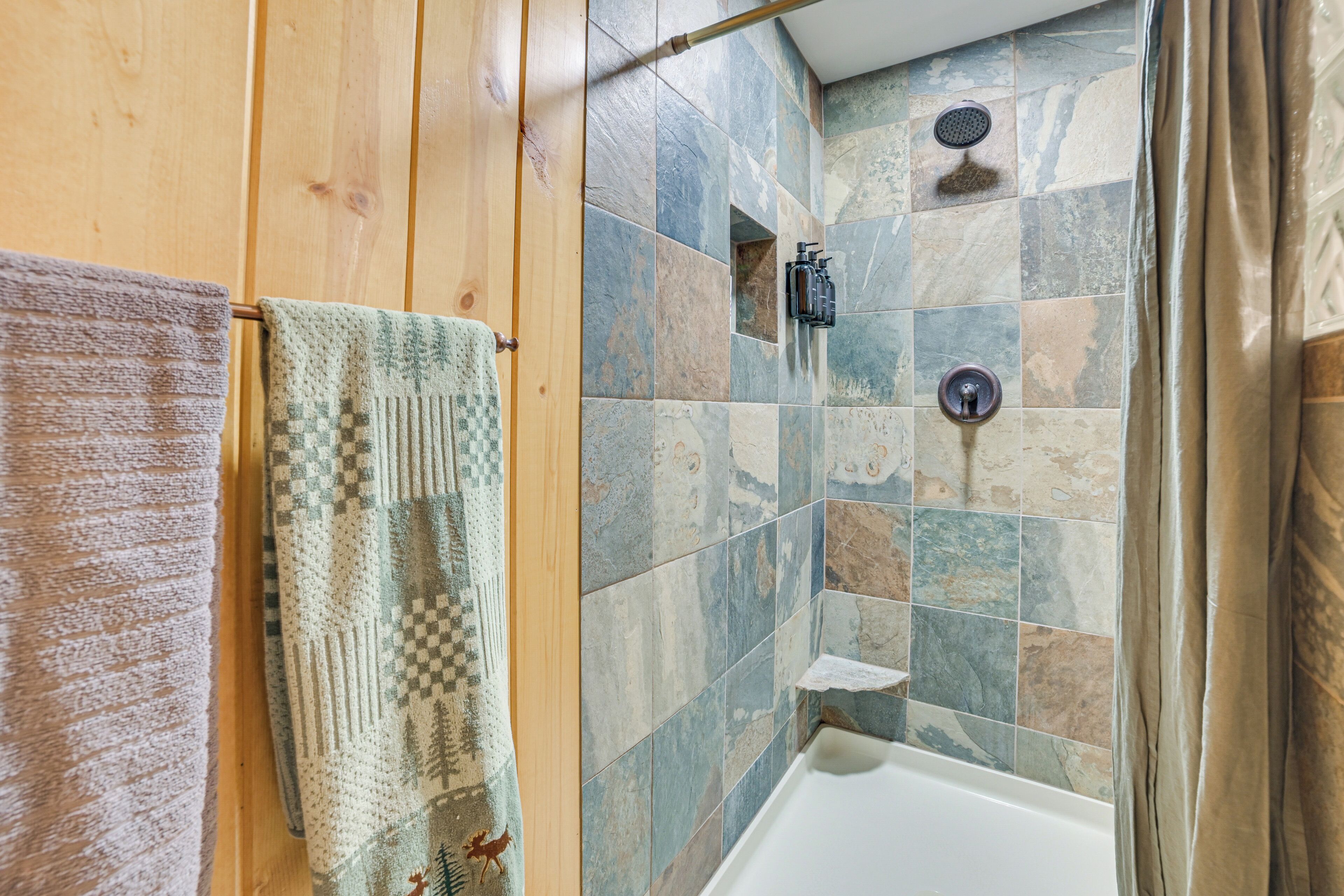 A bathroom with a shower, a towel rack, and a wooden wall.