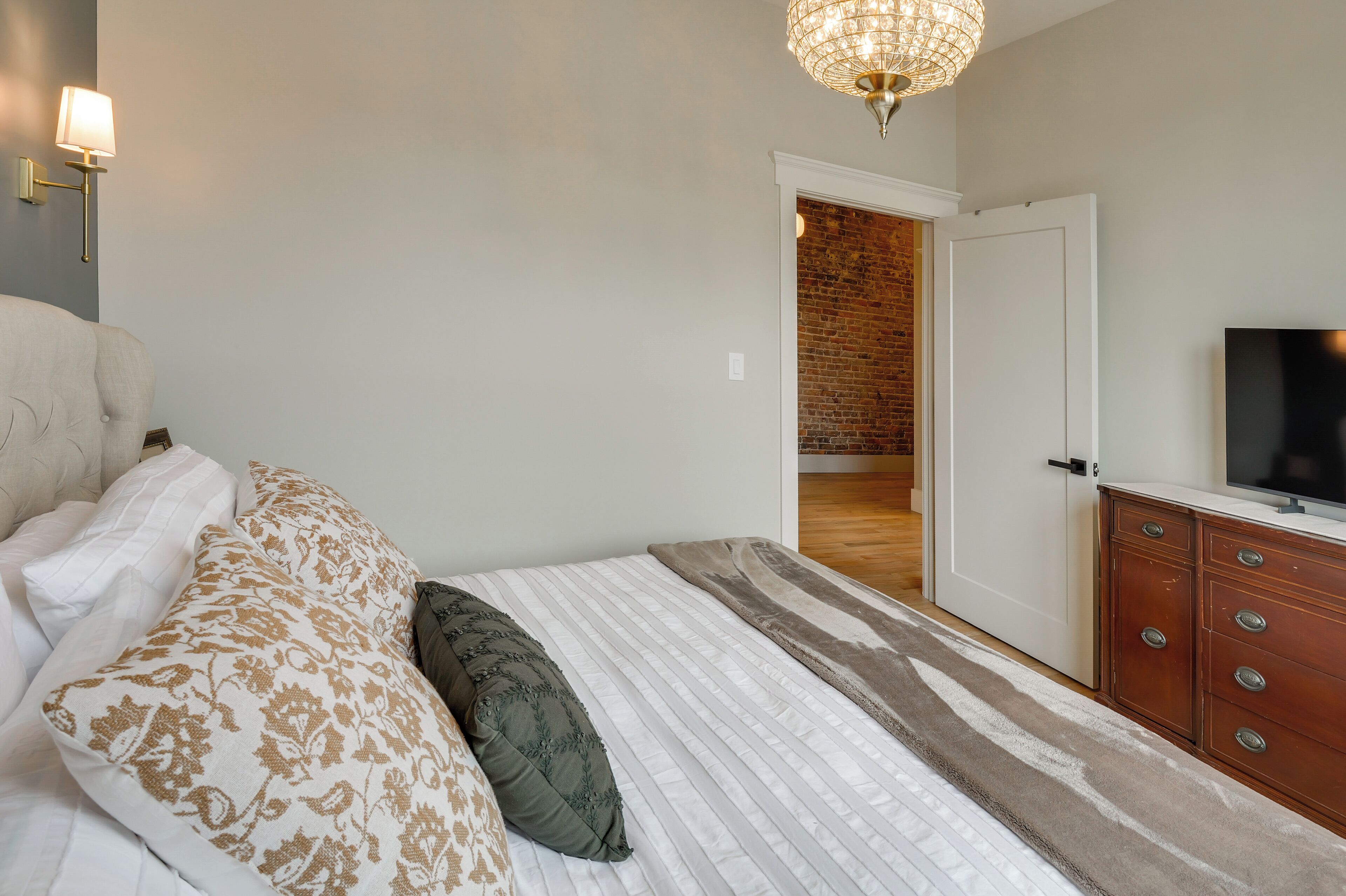 Un dormitorio con cama, televisor, cómoda y candelabro.