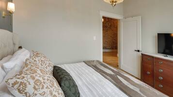 Un dormitorio con cama, televisor, cómoda y candelabro.